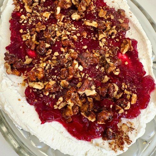 Hot Honey Whipped Goat Cheese Dip with Cranberry & Walnuts 5 Hot Honey Whipped Goat Cheese Dip with Cranberry & Walnuts on a glass platter served at a holiday party.