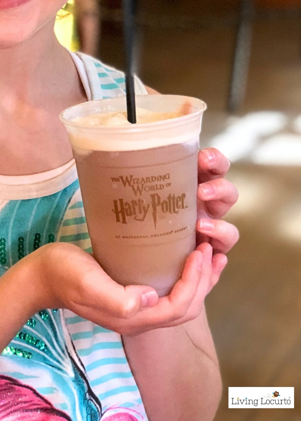 Hand holding a cup of butterbeer from Universal Orlando in the harry potter World